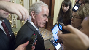 Senatorn Bob Corker anklagas för att ha vänt kappan med vinden efter att han ändrade sin ståndpunkt till skattereformen. Han anklagas också för att gynnas personligen av ett tillägg som ger sänkta skatter på fastighetsvinster. Republikanska senatorn Bob Corker omringad av journalister och mikrofoner.