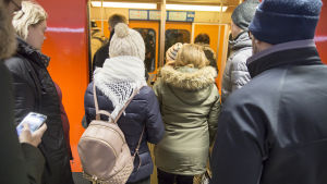Passagerare på väg in i metron. Ihmisiä menossa metrojunaan metroasemalla.