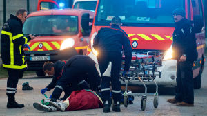 En skadad person får vård efter sammandrabbningarna. En person ligger på marken och får hälsovård efter sammandrabbningar i Calais.
