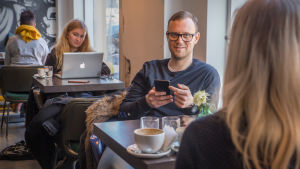 Thomas Kinnaird använder inte Facebook lika ofta som tidigare. Thomas Kinnaird käyttää älypuhelinta kahvila Bergga:ssa.