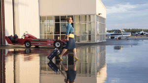 Renée går mot ett flygplan med huvudet högt och kappsäcken käckt på svaj.