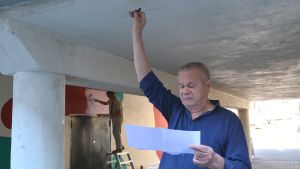 Jaakko Rönkkö planerar kolteckningen. Jaakko Rönkkö sträcker handen mot tunnelns tak med kolkritan i handen, ser på skisspapper i andra handen.