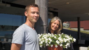 Raine och Pia Kaukainen har fått slita hårt de senaste två månaderna. Raine och Pia Kaukiainen står vid en vit blomma på sin terass