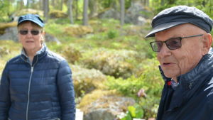 Alf Hjerpe och Karin Westergård Hjerpe undviker helst stugan före mårdproblemet är åtgärdat. alf till höger och karin till vänster. de sitter ute på en terass och har vindtäta kläder på sig. i bakgrunden är det bara skog.