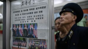 Stort intresse i Nordkorea för nyheter från toppmötet med Trump. Man i uniform läser väggtidning i Nordkorea, med bilder från toppmötet mellan Trump och Kim Jong-Un