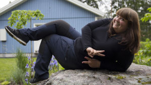 Kristine Vesterlund haluaa innoittaa ihmisiä kokeilemaan rohkeasti oman ruokansa viljelemistä. Trädgårdsmästaren Kristine Vesterlund halvligger på en sten och poserar.