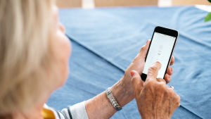 Verkkopankkitunnusten käyttö on hyödyllinen digitaito. Nainen näppäilee puhelimella verkkopankkisovellusta.