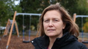 Rektor Mona-Lisa Göthelid. En medelålders kvinna står framför några gungor en höstdag i oktober.