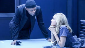 Barely lethal. Nainen istuu ja mies nojaa pöytään huoneessa, joka näyttää kuulusteluhuoneelta.