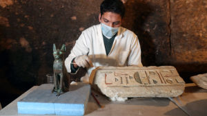 Statyn på bilden föreställer den egyptiska gudinnan Bastet. En bild på en kattstaty och heroglyfer