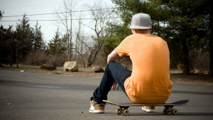Föräldrarna är oroliga för att indelning kan leda till mobbning också i skolan. Arkivbild. En pojke sitter på en skateboard med ryggen mot kameran.