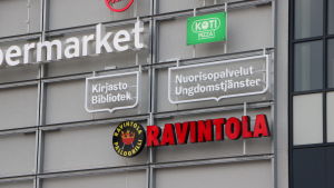 Biblioteket och ungdomsgården finns numera i det nyöppnade köpcentret Saari. Företagslogotyper och skylt för bibliotekstjänster på väggen till köpcentret Saari,