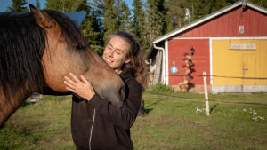 En kvinna står och kelar med en häst.