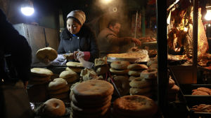 Uigurer på en marknad i Urumqi i Xinjiang Uigurer säljer bröd på en marknad i Xingjiang, Kina