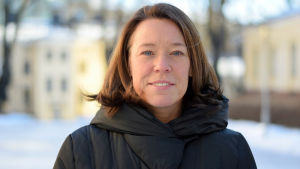 Professor Åsa von Schoultz säger att partierna är strateger som aktar sig för att göra sig omöjliga som samarbetspartners. professor Åsa von Schoultz porträtt utomhus på vintern vid statsvetenskapliga fakulteten med gula byggnader oskarpt i bakgrunden.