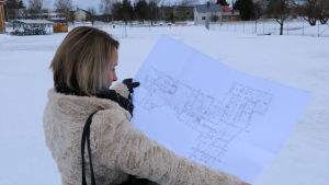 Annika Heikkilä visar ritningarna för det nya daghemmet. En kvinna med axellångt ljust hår visar upp en planritning på en byggnad.