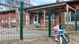 För tillfället är det för trångt för att alla femåringar ska kunna vara i Lilla Alexis lokaler under dagen. En cykel står parkerad utanför en lekplats vid en röd daghemsbyggnad.