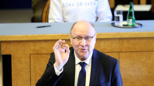 Mart Helme är partiledare för det högerpopulistiska Ekre. Mart Helme står och pratar. Bakom honom skymtar Estlands president i en vit tröja som hon bär i protest mot minskad pressfrihet