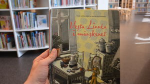 Barnböcker måste plastas. Eller måste de? I ett bibliotek håller en hand i boken "Vesta-Linnéa i månskenet".
