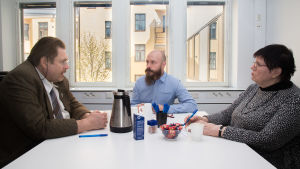 Sami Koivisto kävi tapaamassa Helsingin sovittelutoiminnan sovittelijoita, Jaakko Ojannetta ja Pirjo Työrinojaa, tämän jutun tekemistä varten. Sami Koivisto ja sovittelijat keskustelevat pöydän ääressä Helsingin sovittelutoiminnan tiloissa.