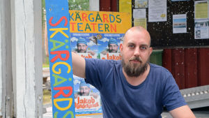 Robert Kock som spelar Jakob Dunderskägg i föreställningen med samma namn. Man sitter och håller i en träskylt.
