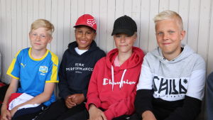 Henrik Grönlund, Elias Yli-Pajula, Elias Pått och Oliver Nygård. Fyra pojkar sitter på en läktare och följer med en fotbollsmatch.