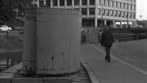 Så här såg toaletterna ut. En gammal spiralformad allmän toalett vid Skatudden i Helsingfors. Bilden är svartvit. En man går förbi toaletten på gatan. Bakom den syns en kanal.