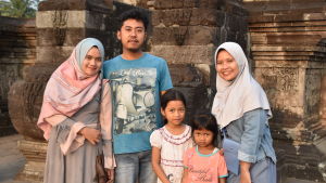 En familj poserar framför ruinerna av ett 700-årigt hindutempel utanför staden Blitar. Ruinerna är ett populärt turistmål. Familj poserar framför tempelruin.