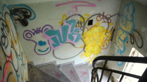 Huset får inte rivas och området skyddas av en hel del regler. En trappuppgång med graffiti på väggarna.