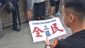 Terry Cheung delade ut affischer åt demonstranterna. I hasten hade det uppstått ett tryckfel i den engelska texten. Terry Cheung delade ut affischer åt demonstranterna. I hasten hade det uppstått ett tryckfel i den engelska texten.