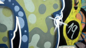 Såväl barn som vuxna har sökt sig till bron för att måla. En närbild av en graffitimålning i blått och grönt på en vägg.