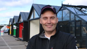 Enligt Stefan Malm måste man anpassa verksamheten till nya former.. En man med keps på huvudet står framför en rad med små bodar.