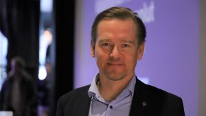 Mika Aalto från Kemiindustrin tycker det är vitkigt att Finland hela tiden värnar om företagens konkurrenskraft. En man med blå skjorta och kavaj som tittar in i kameran.
