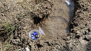 Barnen leker med plastkorkar i lägret Moria på Lesbos, Grekland 20.5.2018 Plastbitar som varit del av lekar för barn ses i en vattenpöl i lägret Moria på Lesbos, Grekland 20.5.2018