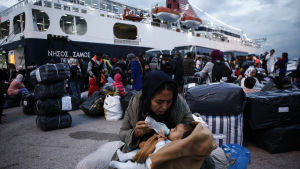 En kvinna matar sin baby efter att ha kommit i land från färjan Nissos Samos som tagit dem från ön Lesbos till hamnen i Pireus, Grekland 7.10.2019. En kvinna matar sin baby efter att ha kommit i land från färjan Nissos Samos som tagit dem från ön Lesbos till hamnen i Pireus, Grekland 7.10.2019