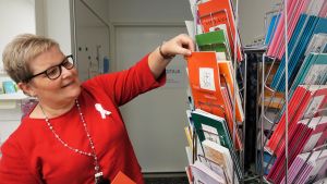 Satu Forsström är rådgivande sjukskötare på Södra Finlands Cancerförening. Hon jobbar med att erbjuda stöd till cancerpatienter och till deras anhöriga. Kvinna visar broschyrer för olika cancerrehabilitering