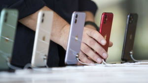 Apple rankas som ett av världens största och mest inflytelserika företag i världen. Fem Iphone 11-telefoner i olika färger på rad i ett köpcentrum i Dubai. En person håller i telefonen som är röd. Telefonerna är fotade så att bara baksidan med Apple-logon syns.