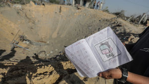 En släkting till dödsoffren visar upp ett skolhäfte som hittades i gropen efter den israeliska flygräden mot Rasmi Abu Malhous i Deir al-Balah. En släkting till dödsoffren visar upp ett skolhäfte som hittades i gropen efter den israeliska flygräden mot Rasmi Abu Malhous i Deir al-Balah.