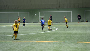 Tränare Kim Friman anser att dagens unga spelare har ett starkare självförtroende än tidigare generationer, och att de vågar satsa på sig själva. Fotbollsspelare från åifk p11-laget och FC Inter spelar fotboll på en fotbollsplan inomhus.