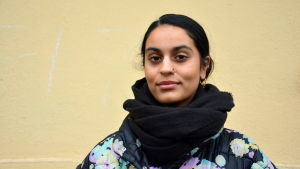 Nayab Ikram ringde direkt till sin syster när hon såg brevet och öppnade det. Hon tyckte det var roligt att få dela glädjen med familjen och hennes nära vänner. en kvinna med pakistanskt ursprung står framför en gul vägg iklädd svart tjock halsduk och blommig tjock jacka.