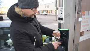 Sami Peltonen är nöjd med sin laddhybrid. Han använder främst el då han kör i centrum. På landsvägen är det bensindrift som gäller. Mies laittaa ladattavan hybridin pistoketta latausasemaan.