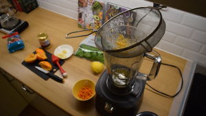 Få en vitaminkick med hemlagad juice. En mixer på ett bord. Frukter och skärbräda på bordet.