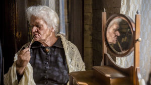 Spegel, spegel på bordet där. Pirkko Saisio är stark som mamma Olga. Helenes mor Olga röker pipa framför en spegel.