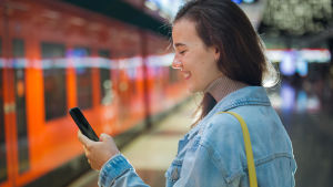 Om du angett din e-postadress i din ansökan, får du antagningsresultatet också i din e-post. En ung kvinna ler och tittar på mobiltelefonen.