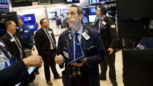 Mäklare i New York stock exchange, världens största marknadsplats. I framtiden kommer marknaden i allt högre grad att delas upp i en majoritet av medelmåttiga och några få framgångsrika bolag. En manlig börsmäklare i kostym och butter min står omringad av andra kostymklädda män med skärmar som visar börskurser omkring.