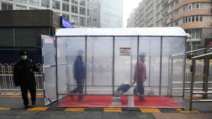 Människor promenerar genom en desinfektionstunnel i Peking 13.2.2020 Människor promenerar genom en desinfektionstunnel i Peking 13.2.2020