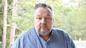 Företaget Potwell och vd:n Teppo Vetoniemi vill kompensera för sina klimatutsläpp. En medelålders man med kragskjorta står på en balkong. Bakom honom syns träd.