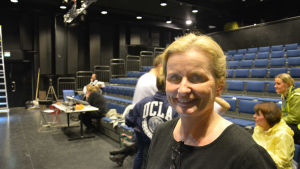 Marina Bergman och hennes man är båda med i revyn. Marina Bergman, en dam med ljust hår och svart skjorta, står i en teatersalong.