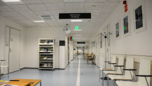 En tom korridor i en hälsocentral. I taker finns en skylt där det står väntrum.