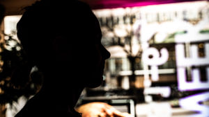 Konfuciusinstitutets närvaro har påverkat möjligheterna att presentera forskningsresultat, säger Tibetforskaren som Spotlight har intervjuat anonymt. En anonym bild (helsvart profil) av en kvinna, med stora fönster, universitetsmiljö, i bakgrunden.